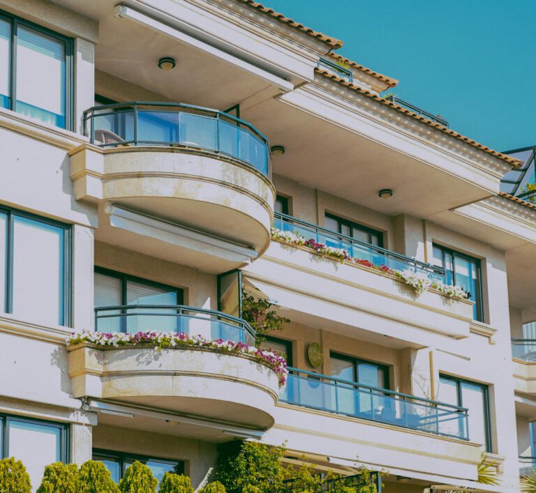 Stylish architecture featuring glass balconies and flower decorations on a sunny day.